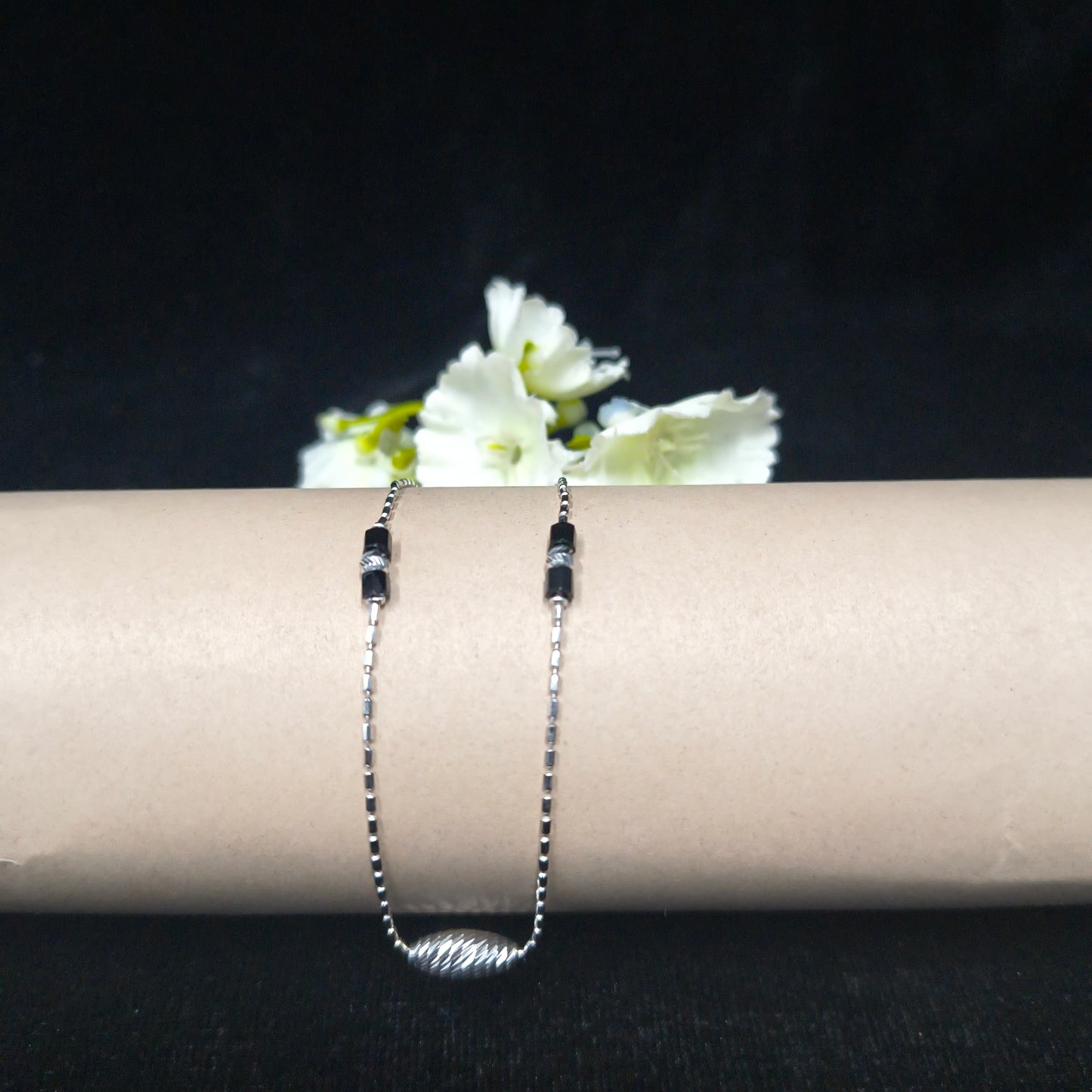 Silver bracelet with white flowers on a black background