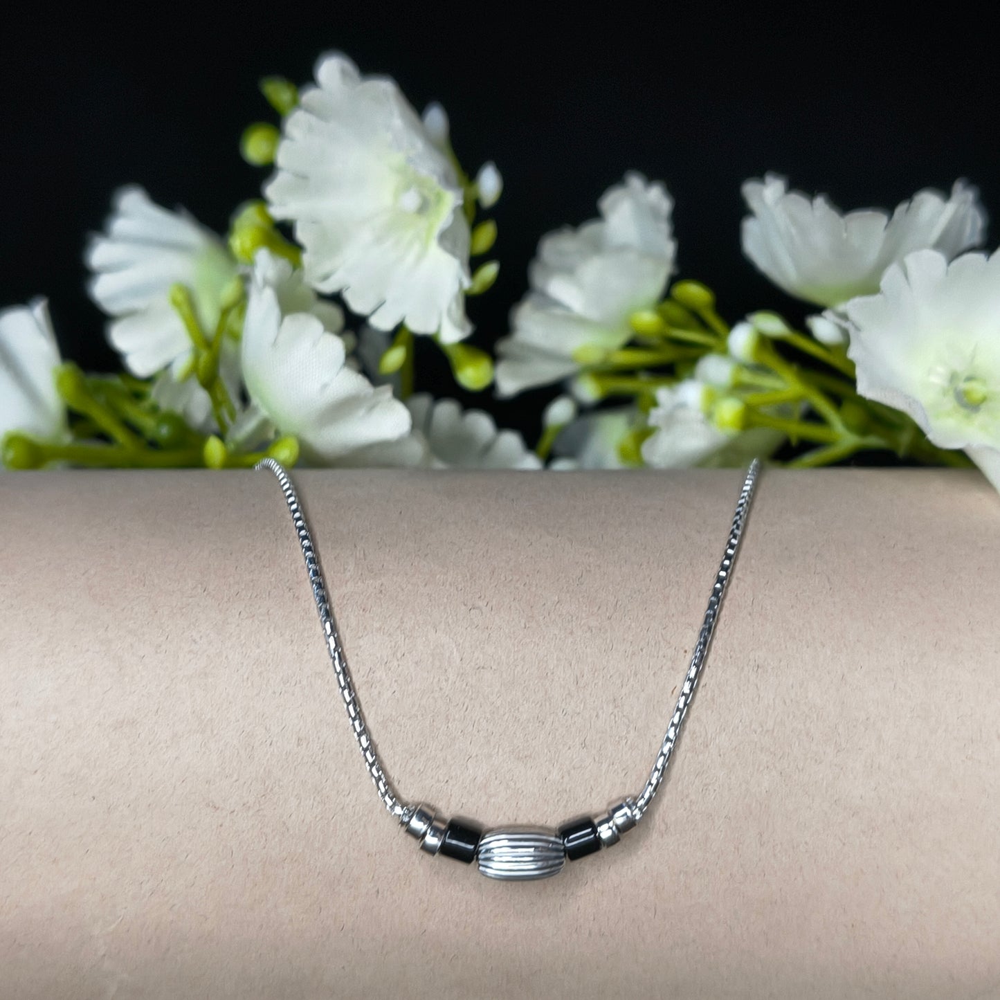 Silver bracelet on a wrist with white flowers in the background