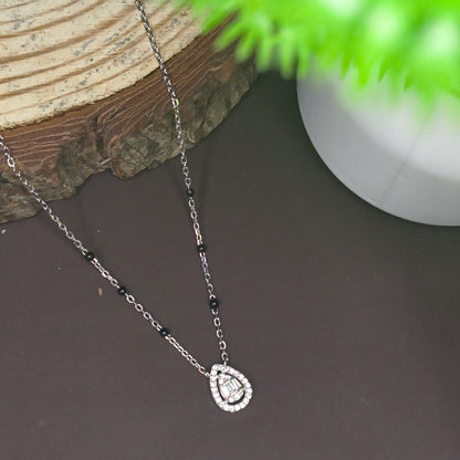 Necklace with a heart-shaped clasp on a dark surface with a plant in the corner