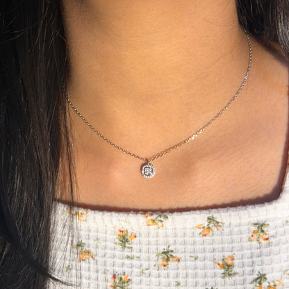 Necklace with a pendant worn by a person, with a floral-patterned garment visible.