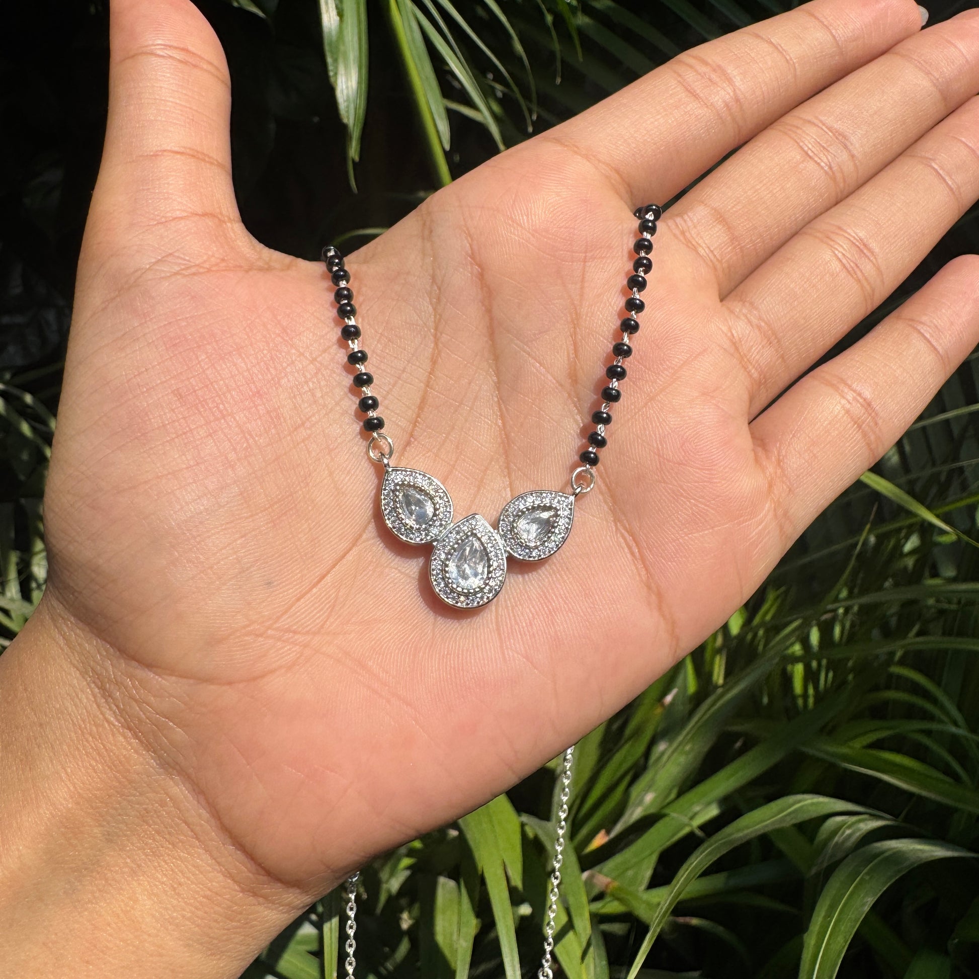 Necklace with a pendant held in a hand against a natural background