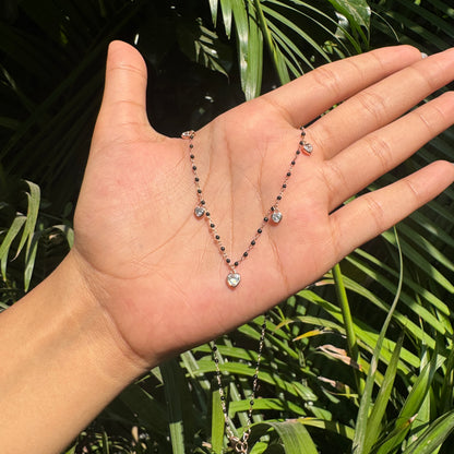 Hand holding a rosary with green foliage in the background