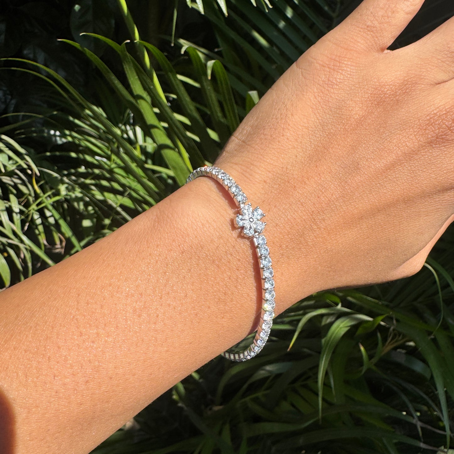 Silver bracelet on a wrist with a green leafy background