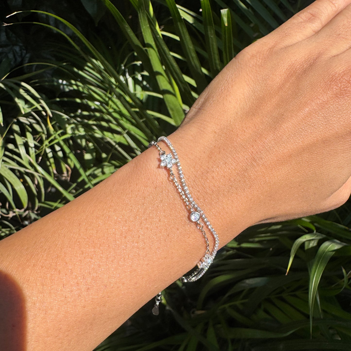 Silver bracelet on a wrist with a green leafy background