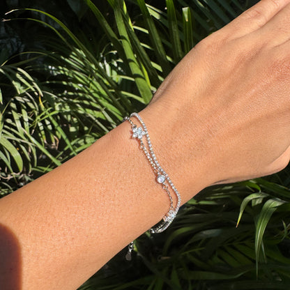 Silver bracelet on a wrist with a green leafy background