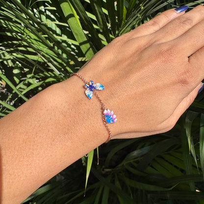 Hand wearing a colorful bracelet with floral designs against a green leafy background