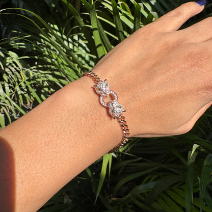Rose gold bracelet with diamonds on a wrist against a green leafy background