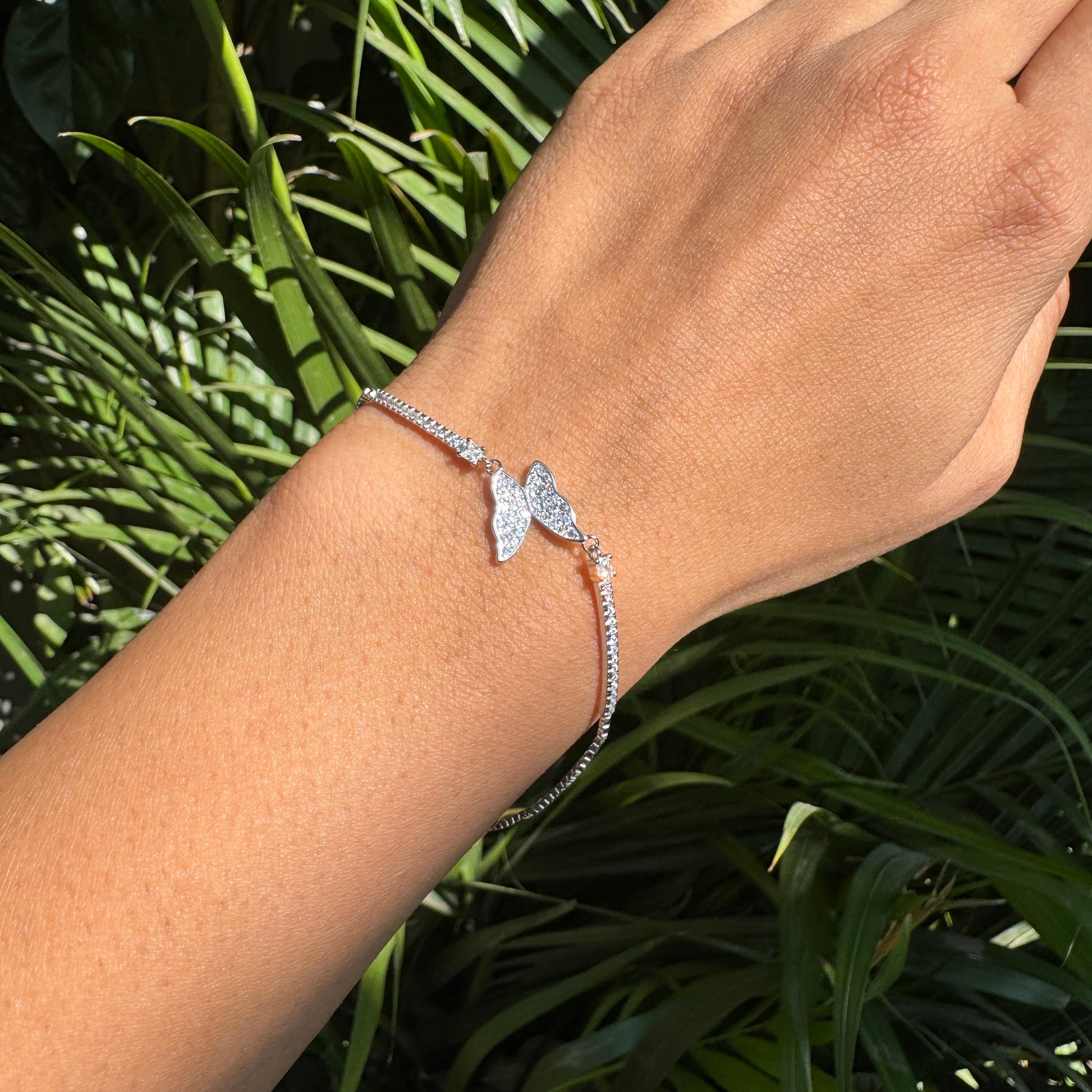 Silver bracelet on a wrist with a green leafy background