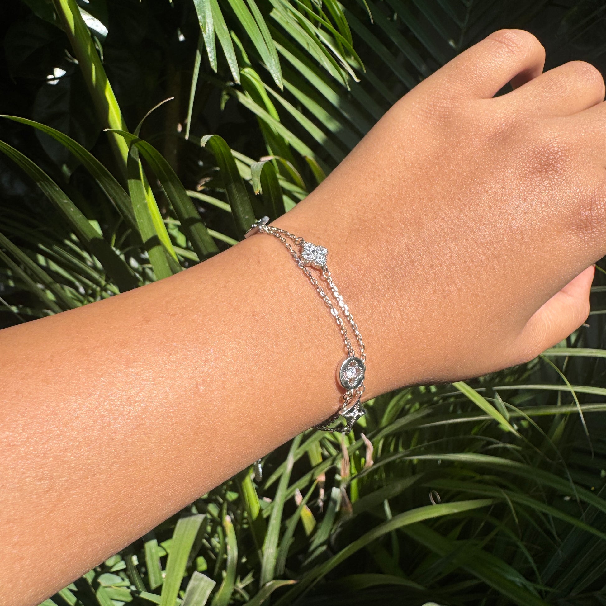 Hand wearing a bracelet with green foliage in the background
