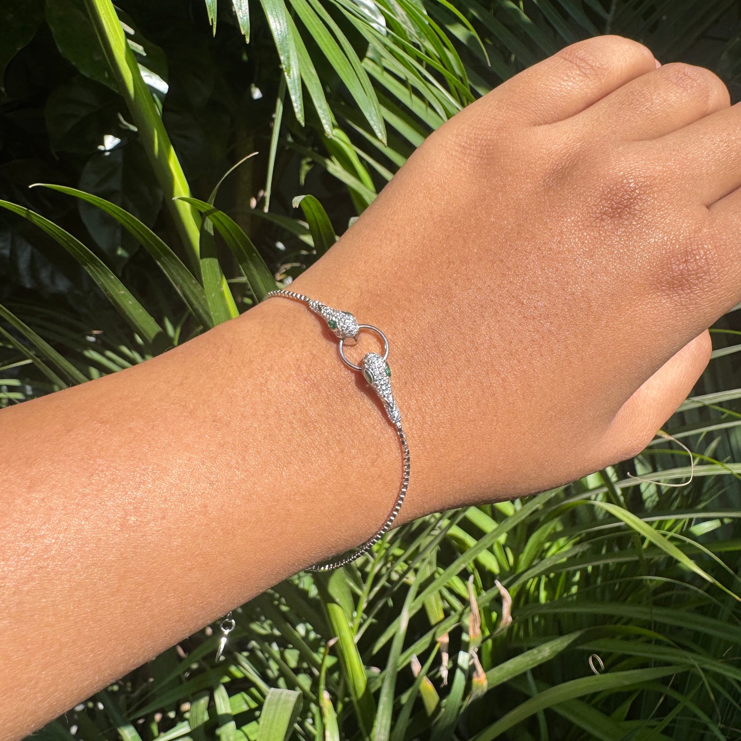 Silver bracelet on a wrist with a green leafy background