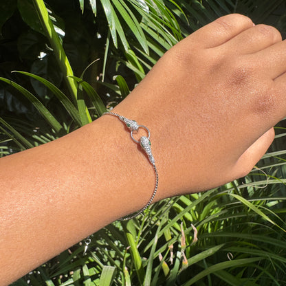 Silver bracelet on a wrist with a green leafy background