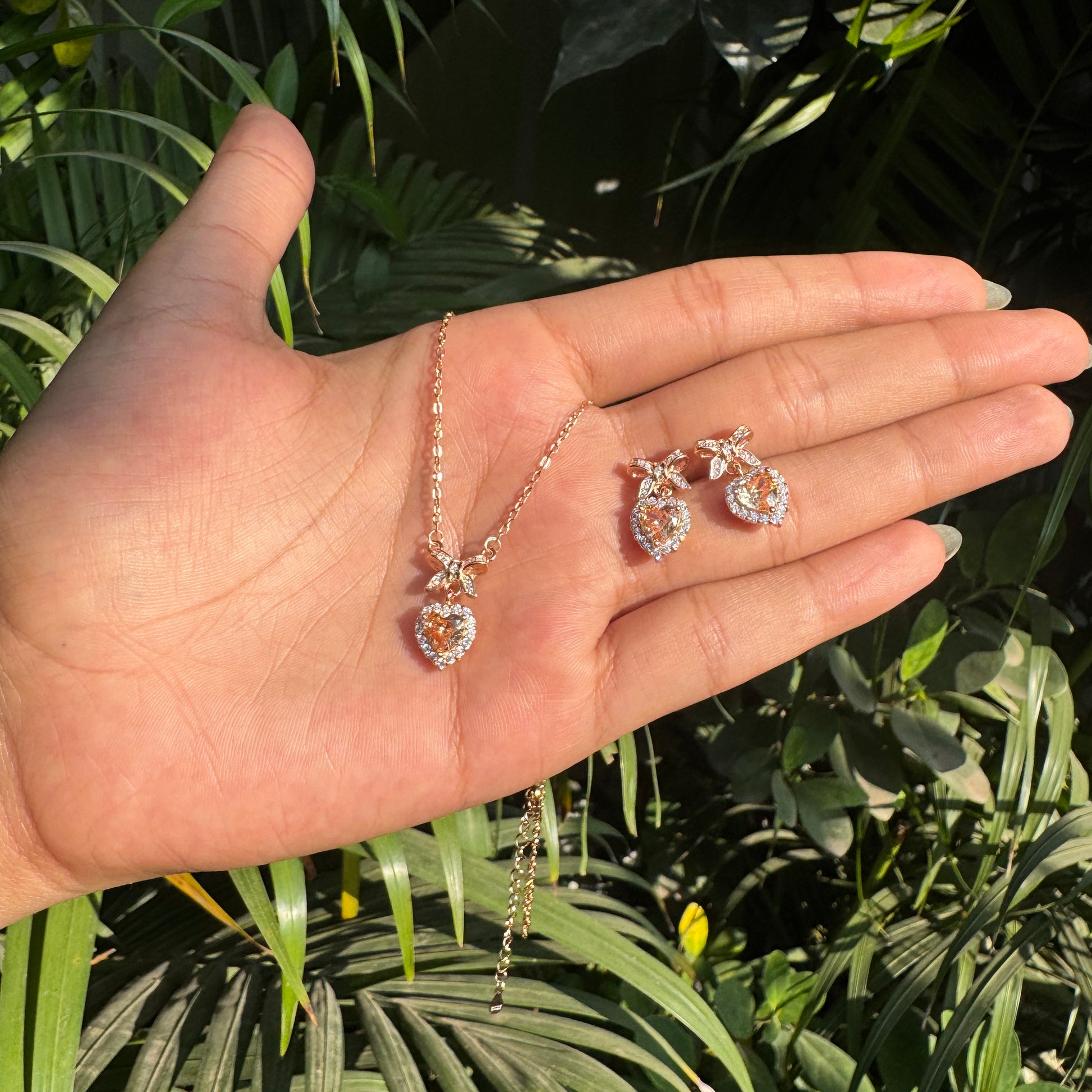 Rose gold jewelry set on a hand with a green leafy background