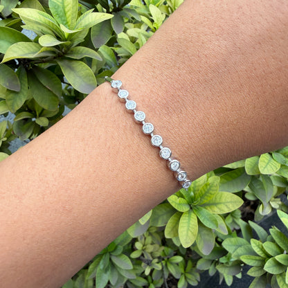 Silver bracelet on a wrist with green leaves in the background
