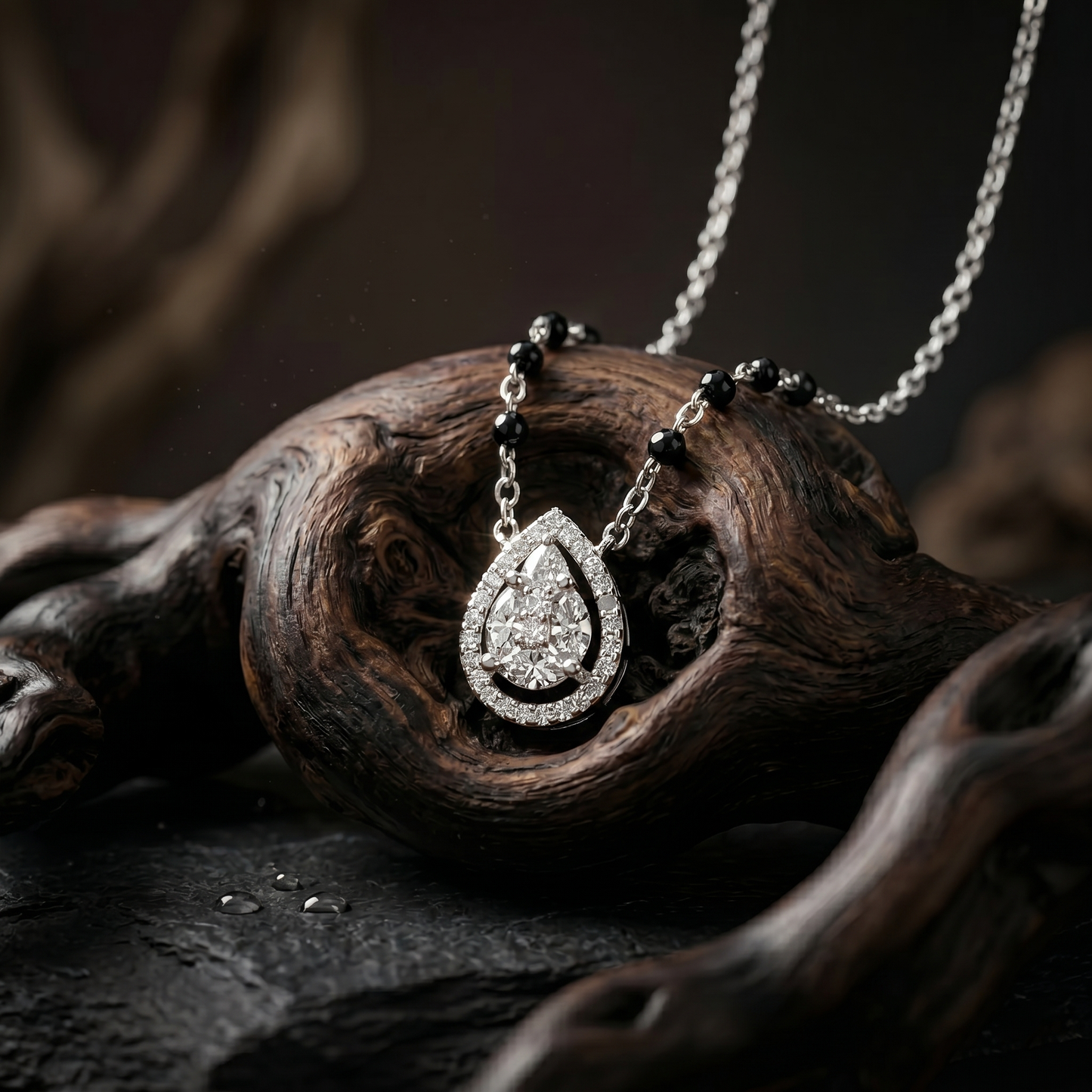 Diamond teardrop pendant on a chain resting on a wooden surface