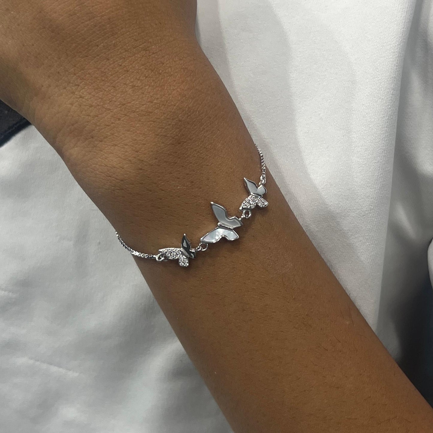 Silver butterfly bracelet on a wrist against a white background