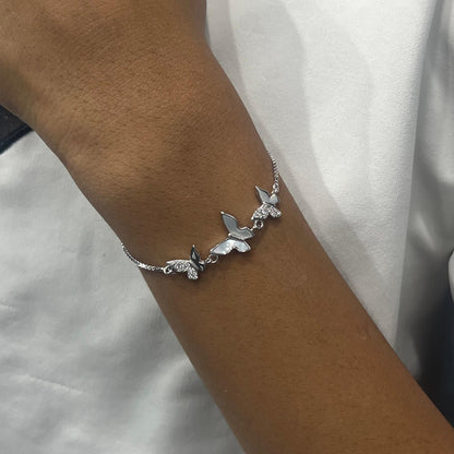 Silver butterfly bracelet on a wrist against a white background