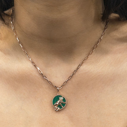 Necklace with a green pendant featuring a cat design on a person's neck.