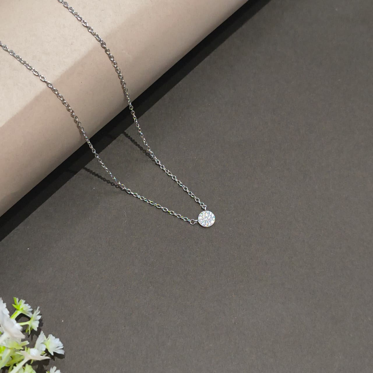 Silver necklace with a round pendant on a gray surface