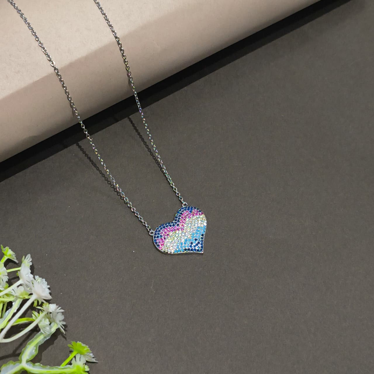 Necklace with a colorful heart-shaped pendant on a dark surface.