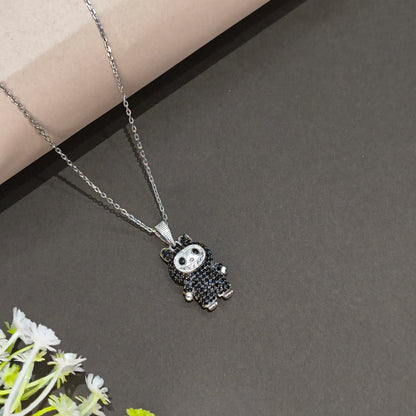 Necklace with panda-shaped pendant on a dark surface with flowers