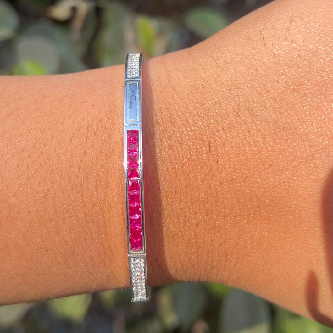Silver bracelet with red stones on a wrist against a blurred natural background
