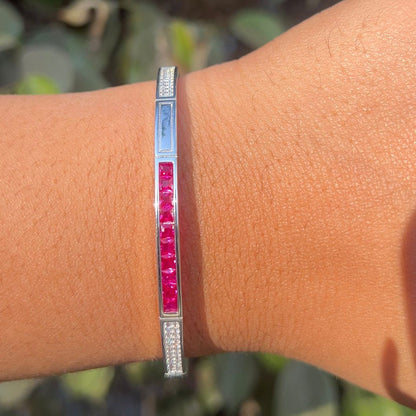 Silver bracelet with red stones on a wrist against a blurred natural background