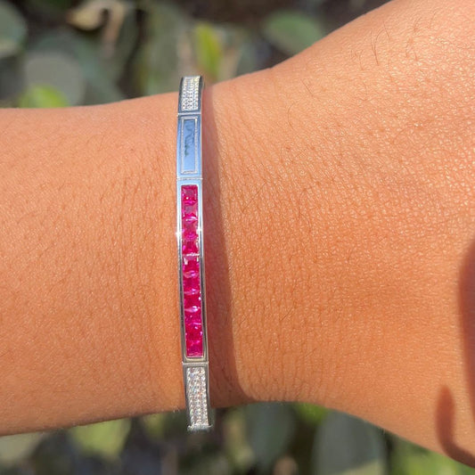 Silver bracelet with red stones on a wrist against a blurred natural background