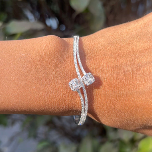 Silver bracelet with two clear gemstones on a wrist against a blurred natural background