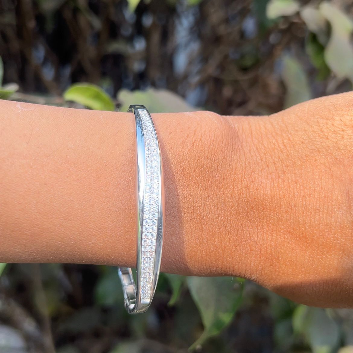 Silver bracelet on a wrist with a blurred natural background