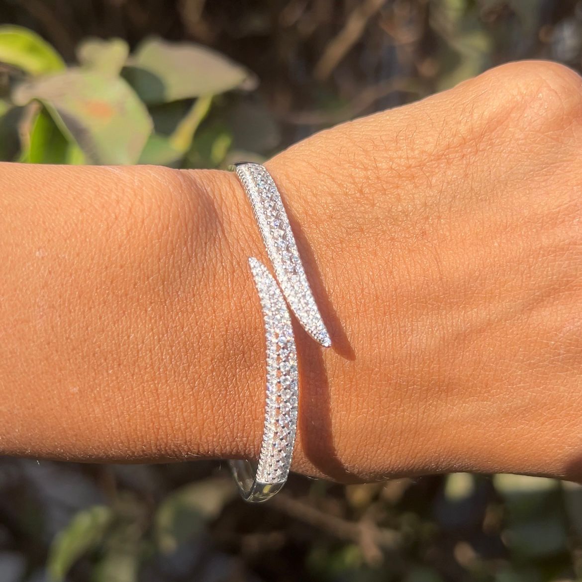 Silver bracelet on a wrist with a blurred natural background