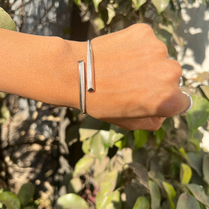 Hand wearing a silver bracelet with a natural background