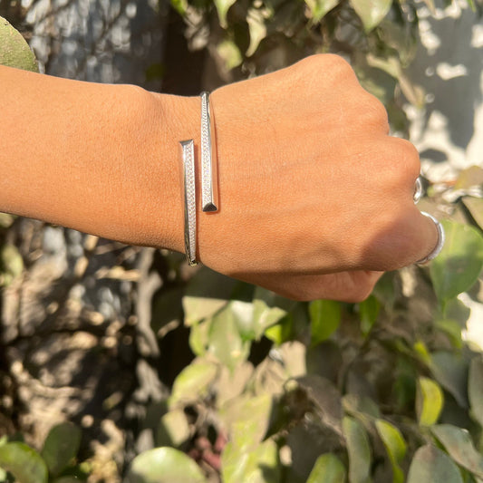 Hand wearing a silver bracelet with a natural background
