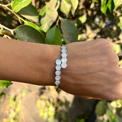 Hexagonal patterned bracelet on a wrist with a natural green background