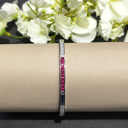 Bracelet with red stones on a beige surface with white flowers in the background