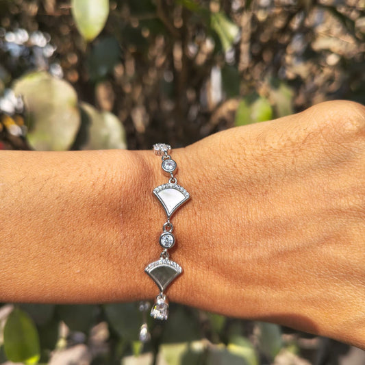 Silver bracelet on a wrist with a blurred green background