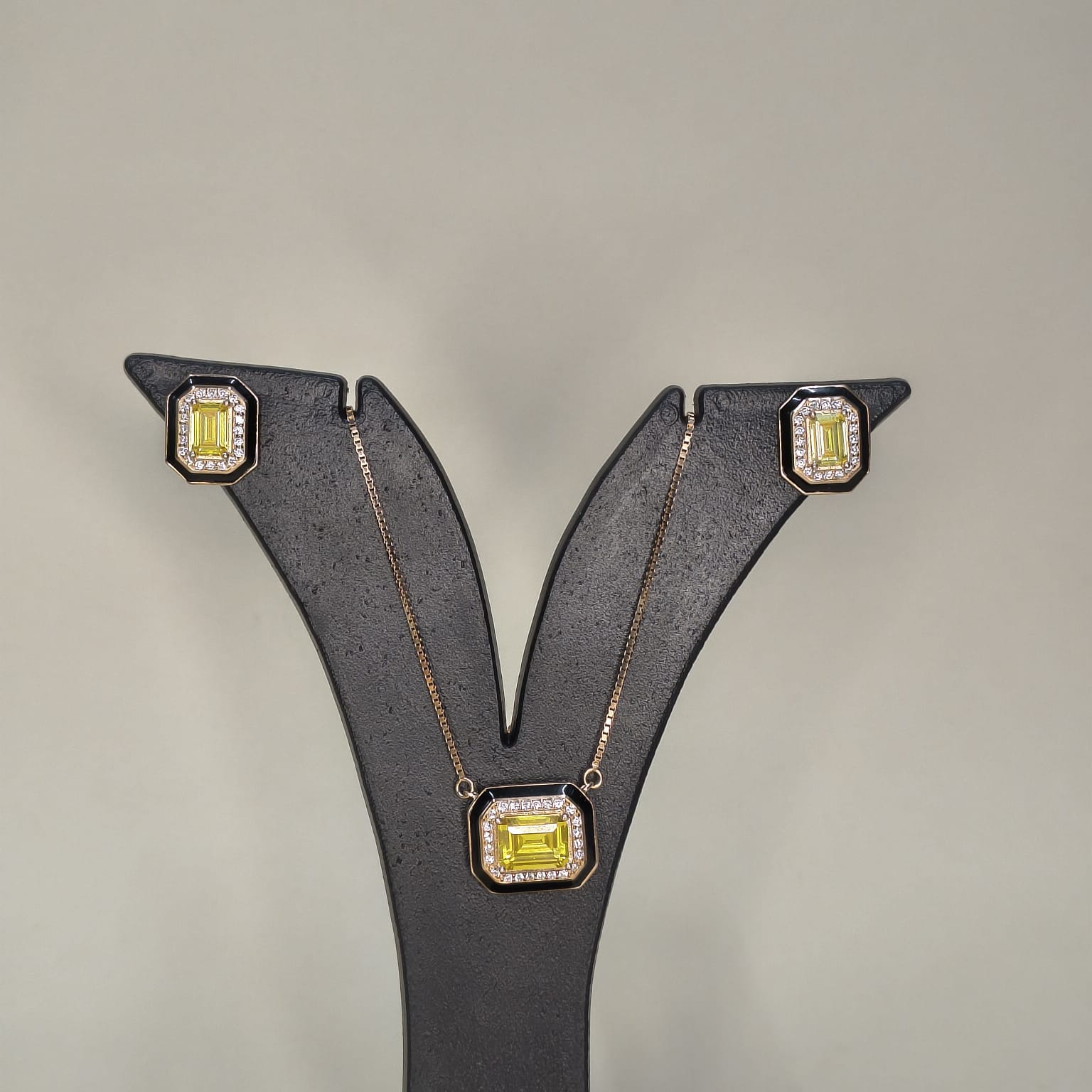 Jewelry set with earrings and a necklace featuring yellow gemstones on a gray background