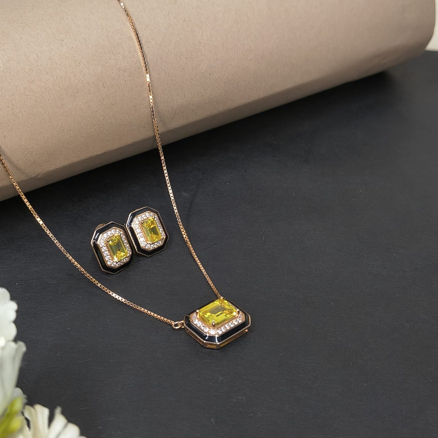 Jewelry set with necklace and earrings featuring yellow gemstones on a dark surface.