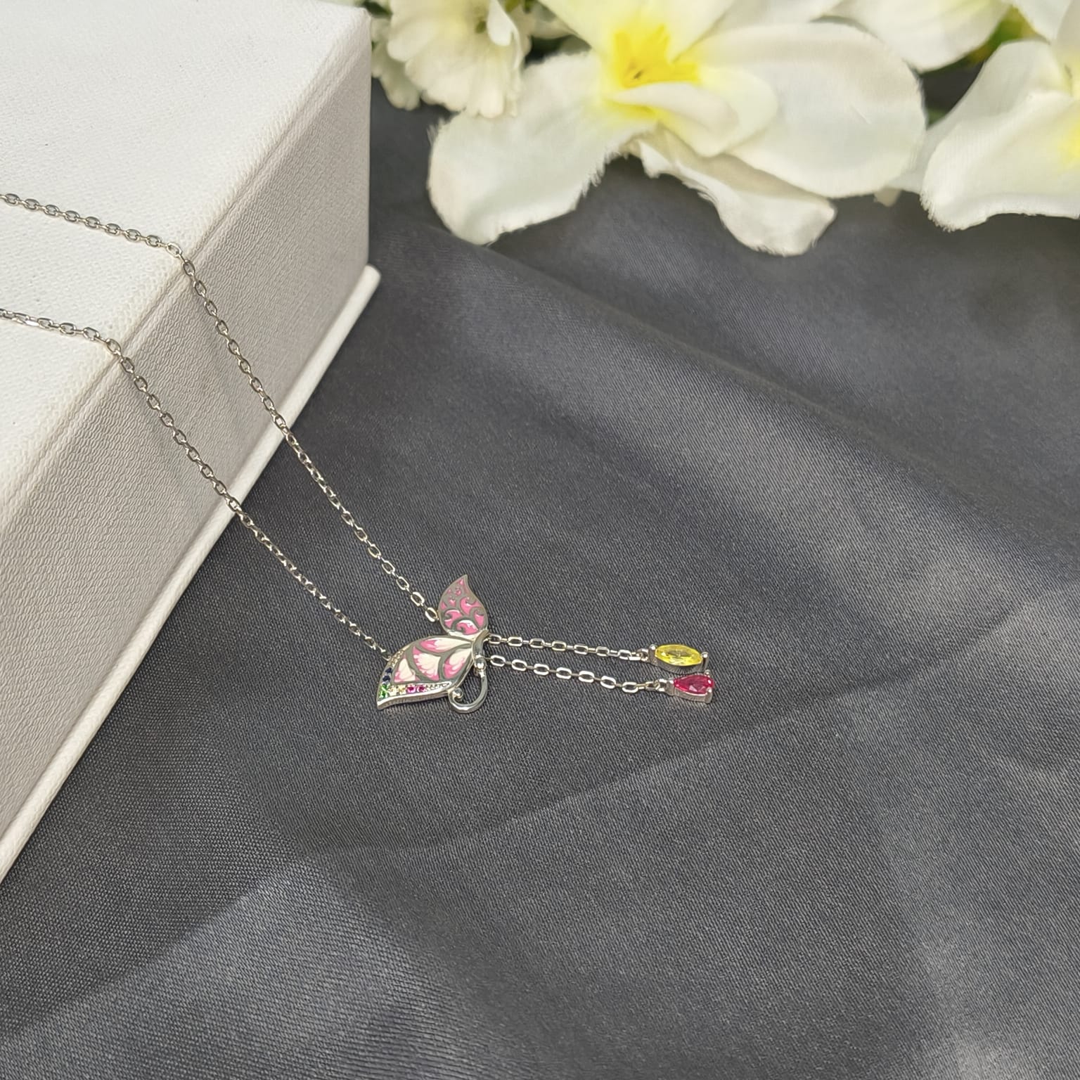 Necklace with a butterfly pendant on a gray surface with flowers in the background
