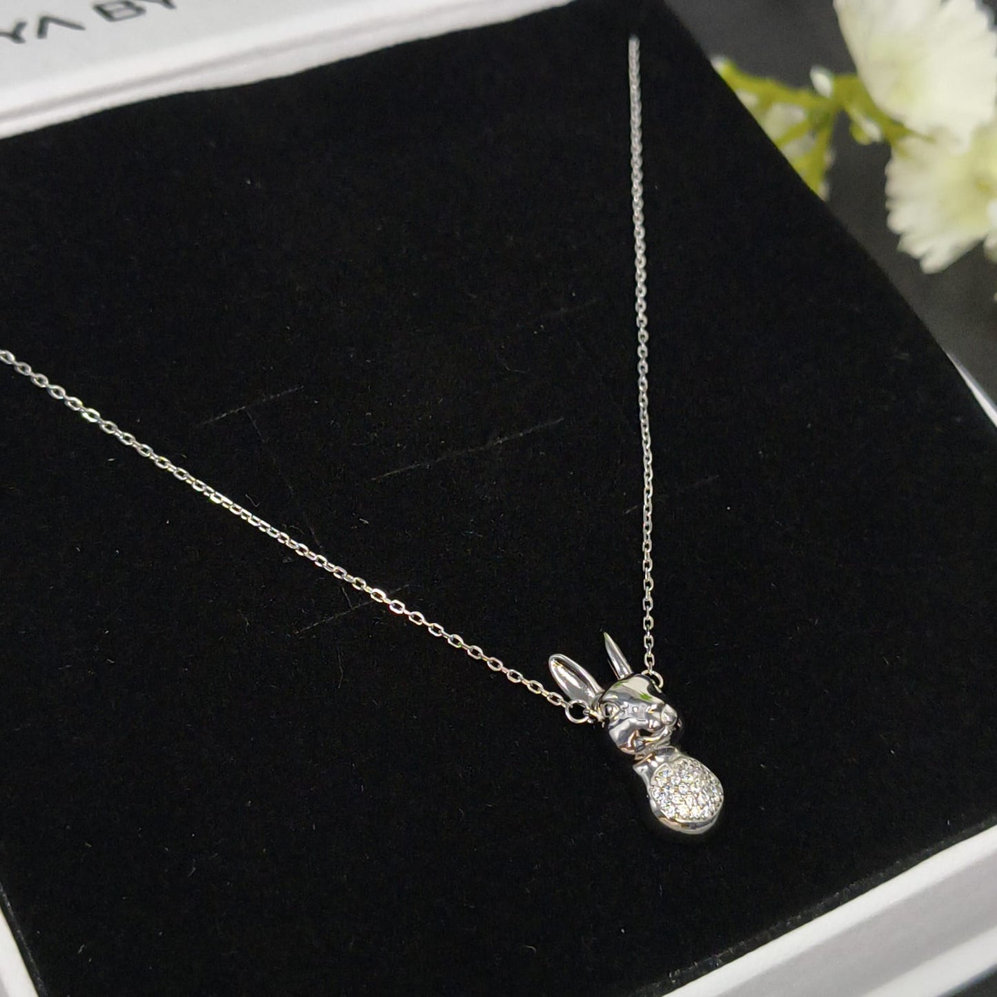Silver necklace with a small pendant on a black velvet surface