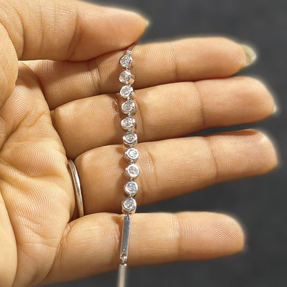 Diamond bracelet held between fingers against a neutral background
