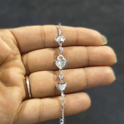 Silver heart-shaped bracelet on a hand with a dark background