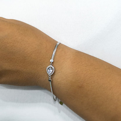 Silver bracelet with a heart-shaped gemstone on a wrist against a white background
