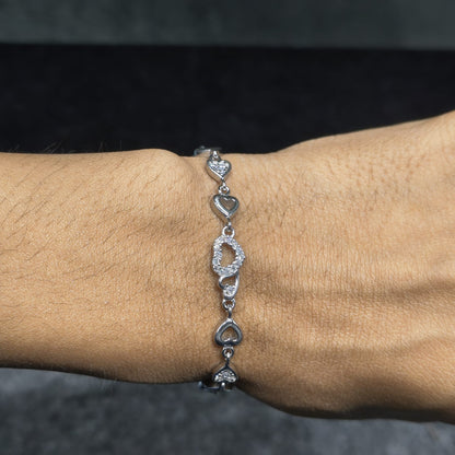 Silver bracelet with heart-shaped links on a wrist against a dark background