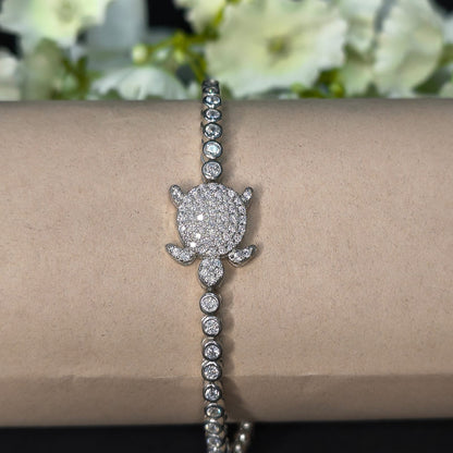 Silver bracelet with a diamond flower clasp on a wrist, with flowers in the background