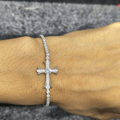 Silver cross bracelet on a wrist with a blurred background