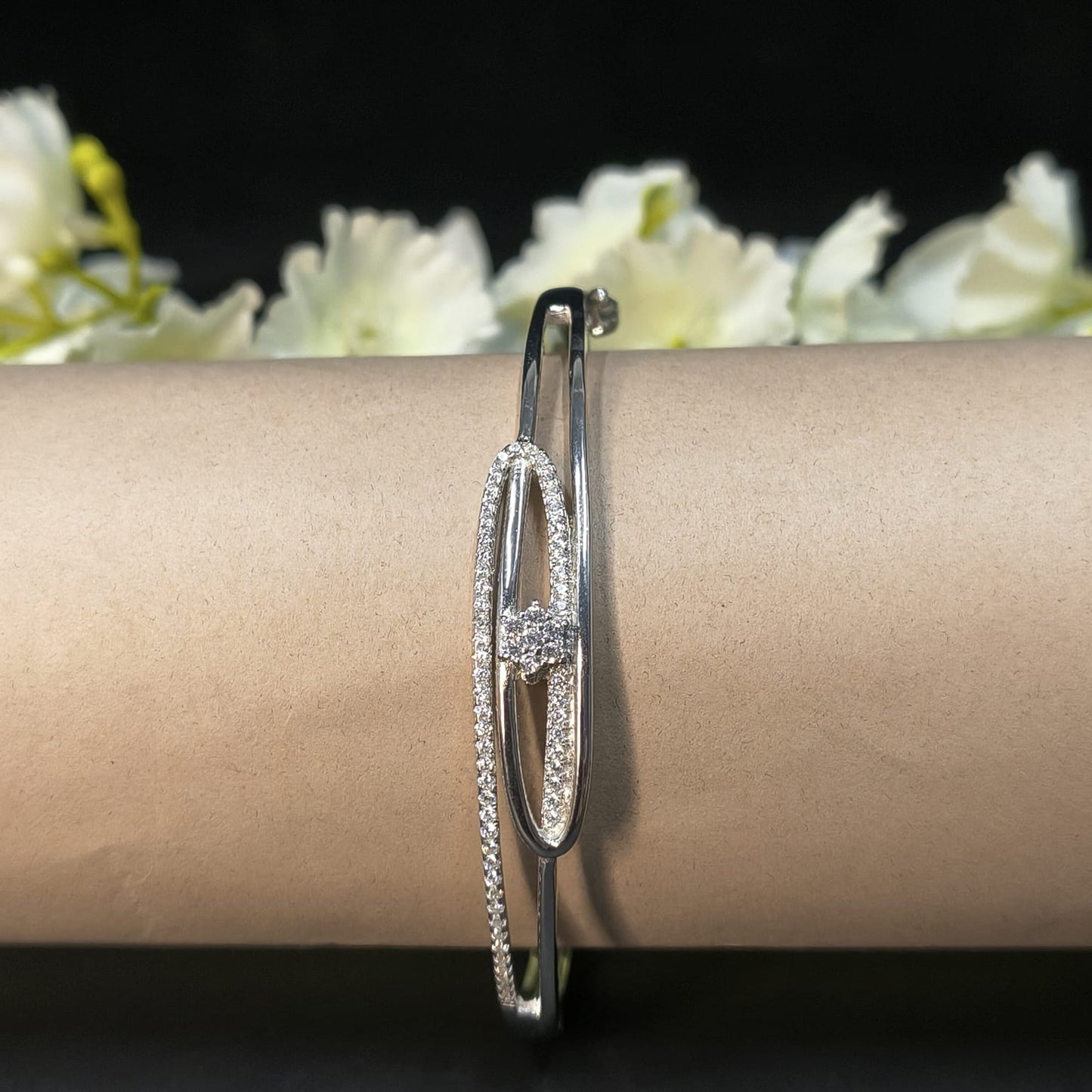 Silver bracelet on a person's wrist with a blurred floral background