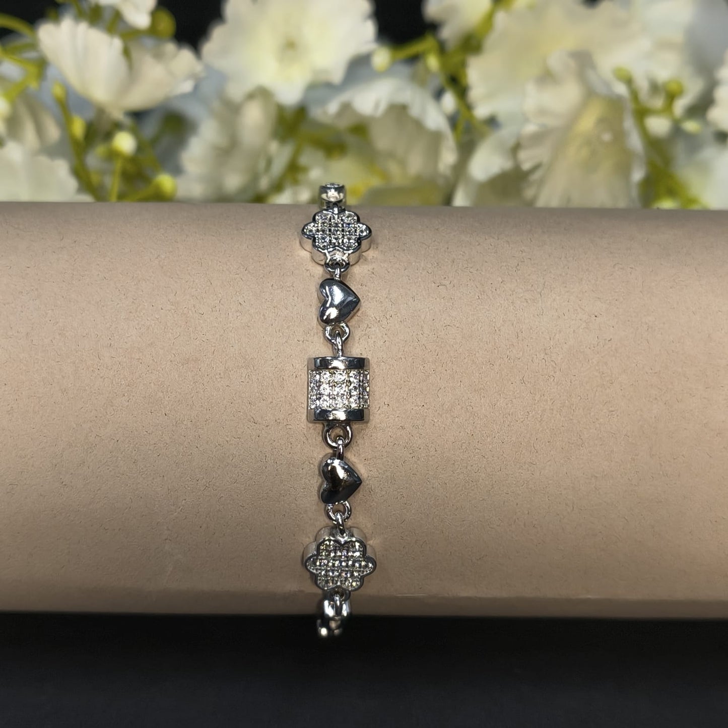 Silver bracelet on a wrist with a blurred floral background