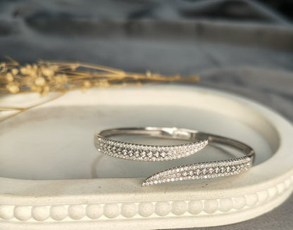Silver bracelet with small diamonds on a white surface with a blurred background