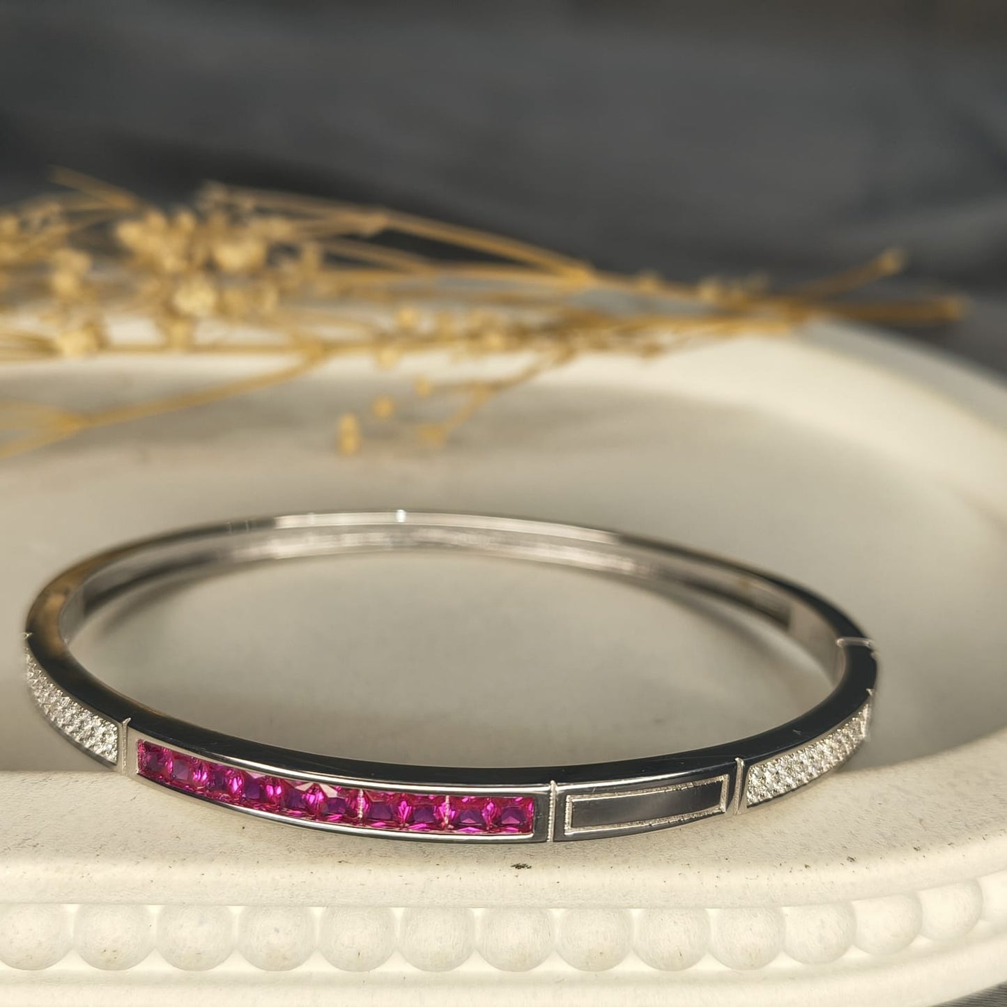 Silver bracelet with pink stones on a textured surface