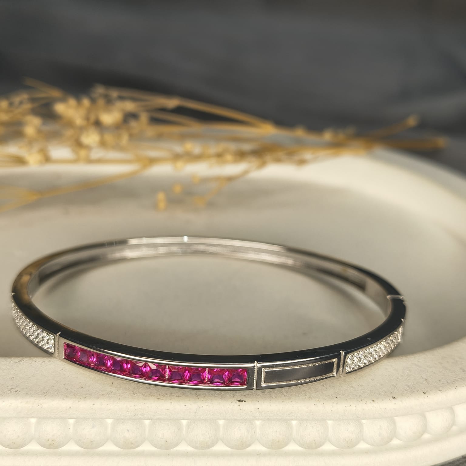 Silver bracelet with pink stones on a textured surface